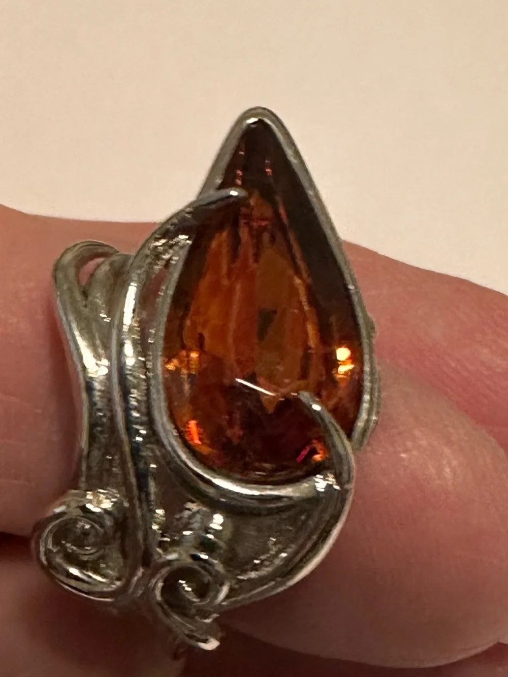 Ring in silver metal intricate with teardrop shaped amber color stone